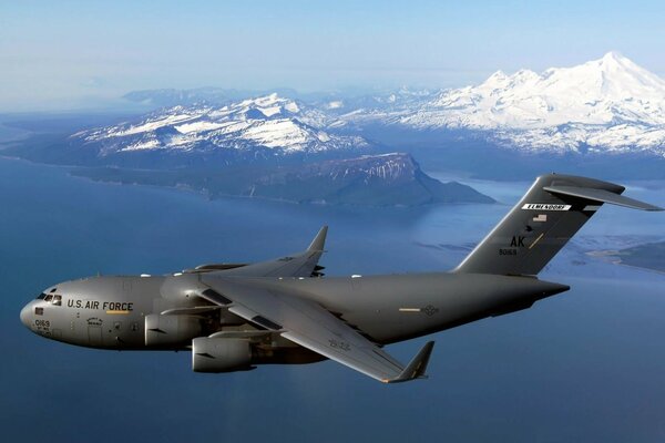 American Boeing in flight over the sea and snow-covered hills