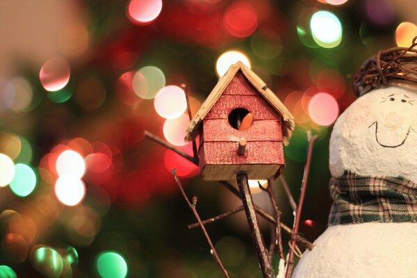 Festive toys snowman and birdhouse on the background of a garland