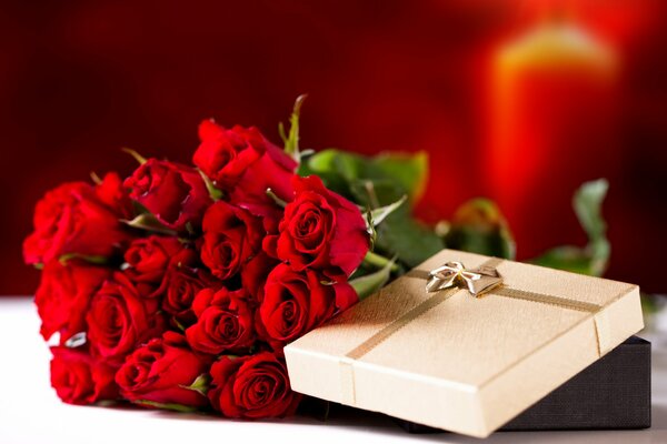 A bouquet of red roses next to the gift