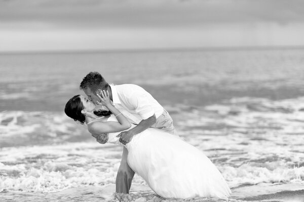 Dolce bacio della sposa e dello sposo in riva al mare