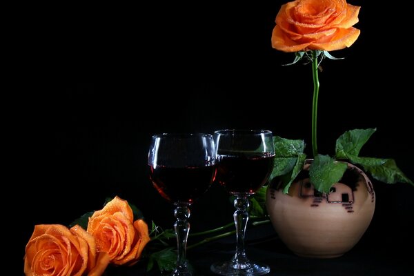 Una rosa naranja en una maceta y dos copas de vino