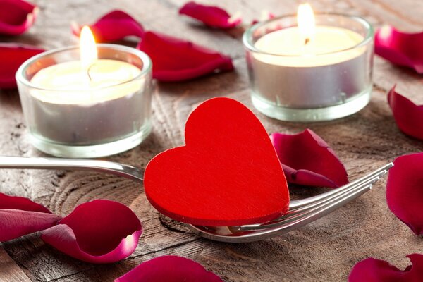 A heart on a fork, candles. Rose petals