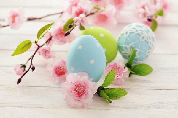 Easter eggs lie next to pink flowers