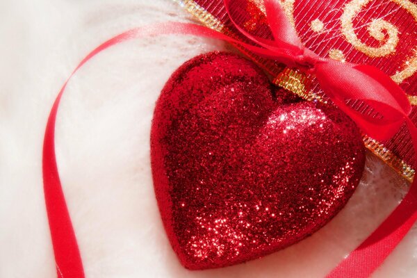 Christmas tree toy in the shape of a heart studded with sequins and a red ribbon