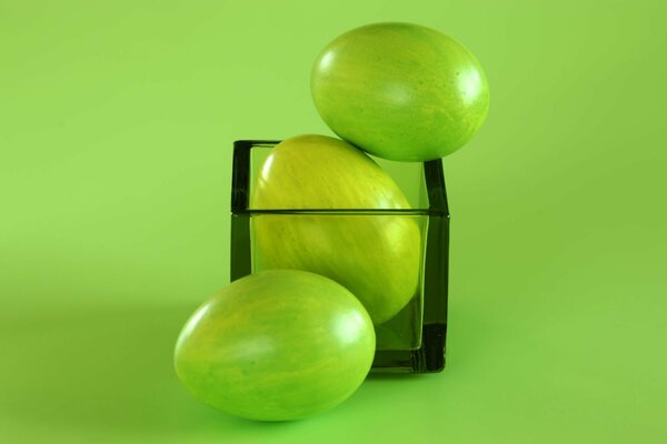 Easter eggs on a green background with a glass