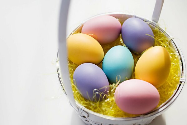 Oeufs de Pâques peints dans un panier sur fond blanc