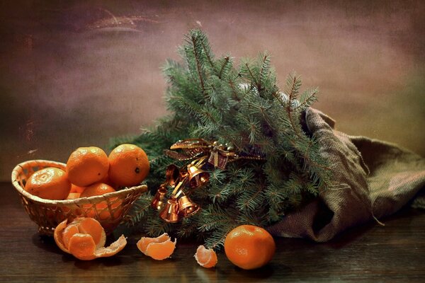 Mandarinas en una canasta cerca de una rama de árbol de Navidad