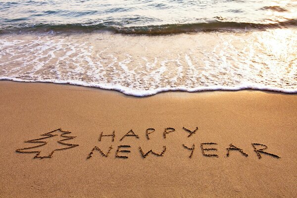 Félicitations sur le sable au bord de la mer bonne année