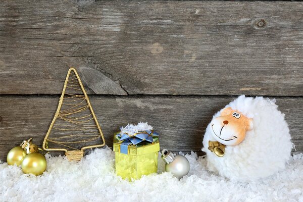 Flauschige Ziege im Schnee mit Geschenken und einem Weihnachtsbaum