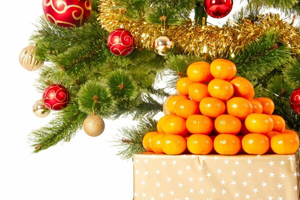 A Christmas tree decorated for the new year with a mountain of tangerines under it