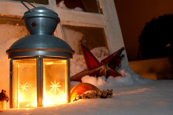 Christmas hand lantern candle in the snow and cinnamon sticks