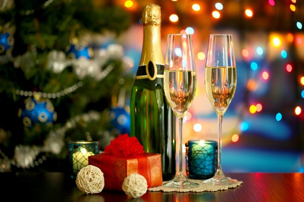 Champagne e due bicchieri sullo sfondo di un albero di Natale