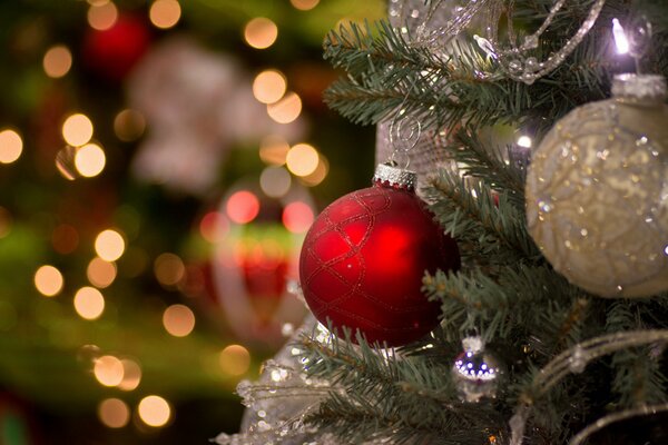 Zwei Christbaumkugeln hängen am Weihnachtsbaum vor dem Hintergrund der Lichter