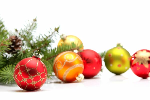 Boules de Noël multicolores et une branche de sapin avec une pomme de pin sur fond blanc