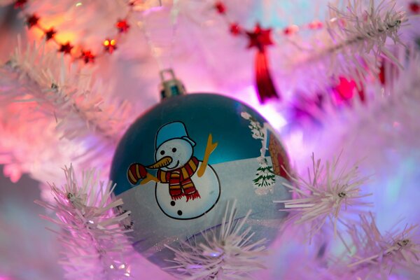 Boule de jouet de Noël avec bonhomme de neige accroché sur un arbre de Noël blanc