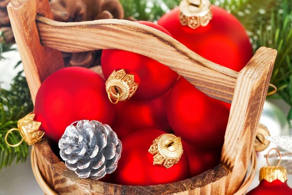 Palle di Natale rosse e coni giacciono in una vasca di legno