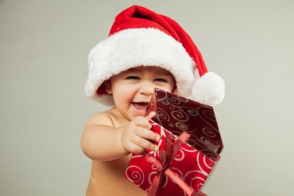 Un niño sonriente con una gorra de papá Noel y con un regalo