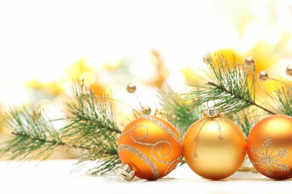 Tres bolas de árbol de Navidad de oro y una rama de abeto