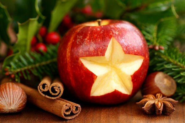 Apfel mit sternförmigem Ausschnitt und Zimt in der Nähe des Weihnachtsbaums