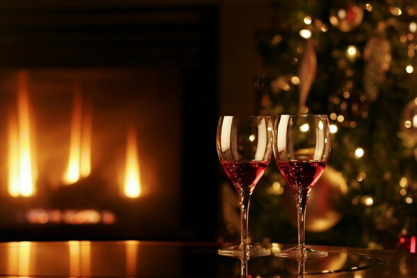 A festive fire in the fireplace. Glasses and a Christmas tree