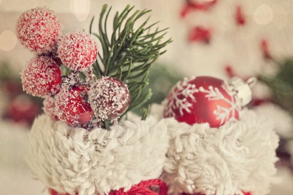 Rot-weiße Stiefel für Weihnachten, verziert mit Beeren, einem Zweig und einem Ball