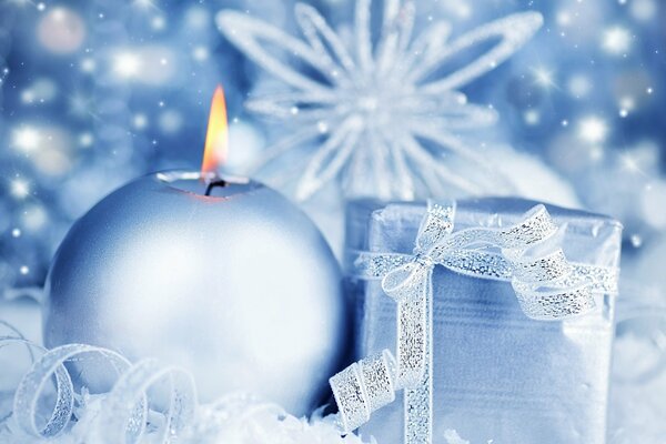 A burning candle and a gift on snowflakes