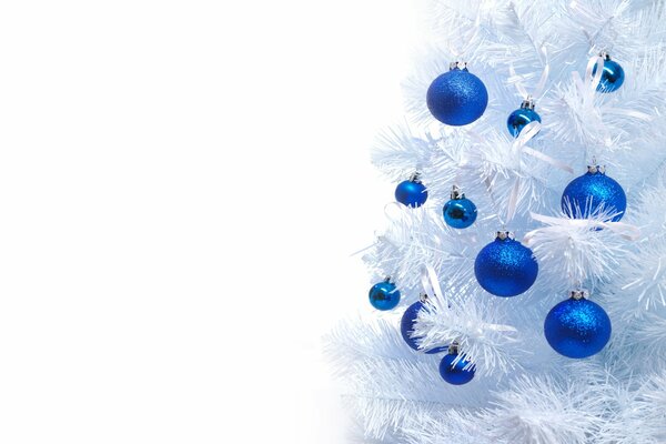 Bolas azules en un árbol de Navidad blanco como la nieve