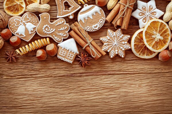 Galletas de Navidad con glaseado blanco, palitos de canela y naranjas secas en una mesa de madera