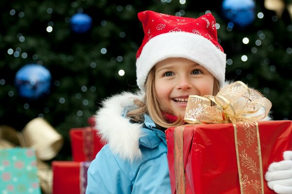 La ragazza nel cappello di Babbo Natale tiene un regalo