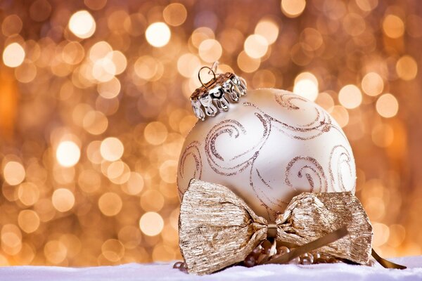 Christmas tree painted ball with a golden bow on a background of bright lights