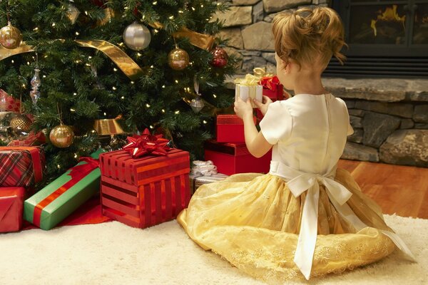 Fille en robe avec des cadeaux près de l arbre de Noël