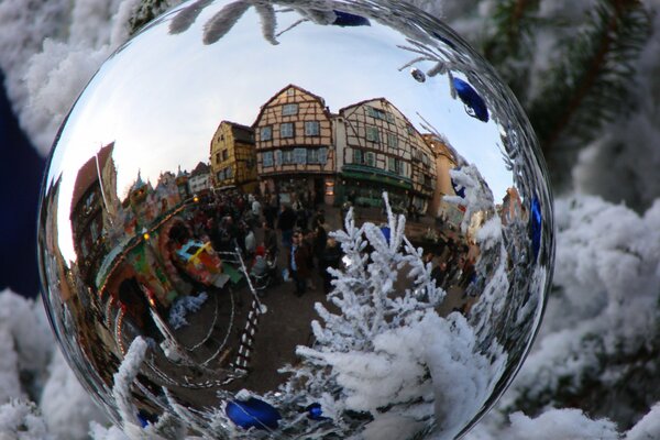 Die Reflexion einer schönen Stadt in einem Neujahrsball auf einem schneebedeckten Weihnachtsbaum