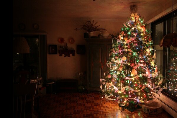 Night. Christmas tree with lighted garlands in the apartment