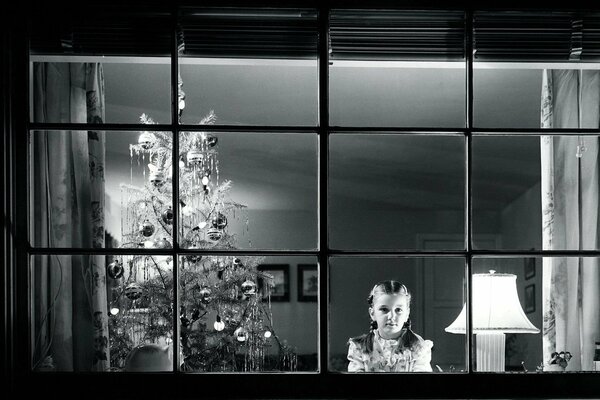 A girl near the Christmas tree , who is waiting for the new year