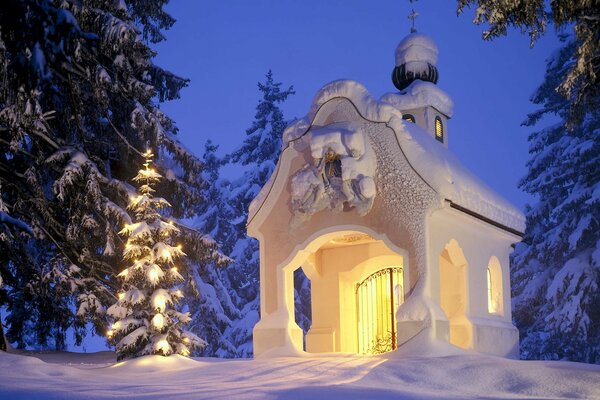 Árbol de Navidad con guirnalda cerca de la Capilla en invierno