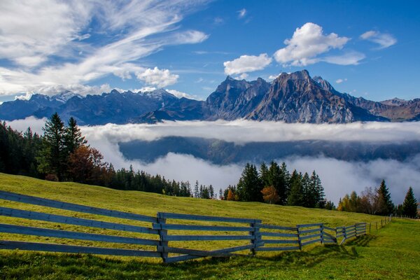 Alpine mountains, green grass and clouds