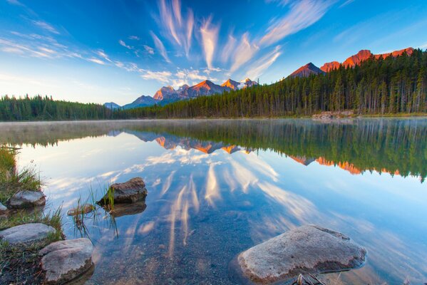 The surface of the lake reflects the mountains and clouds of sunset