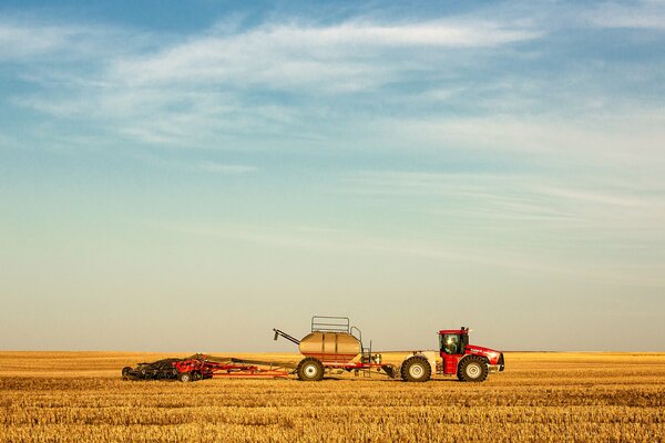 Tractor on the background of a yellow field and blue sky