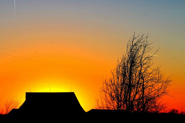 Au-dessus de la maison, le ciel orne le coucher de soleil rouge