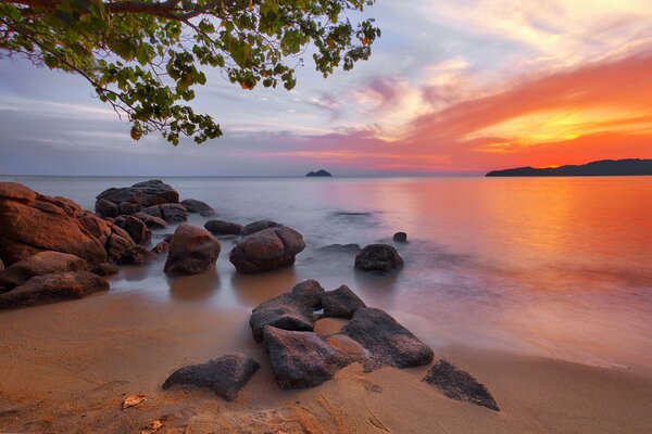 Hermosa puesta de sol en la orilla con piedras