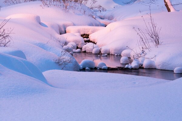 Ein Bach in riesigen Schneewehen