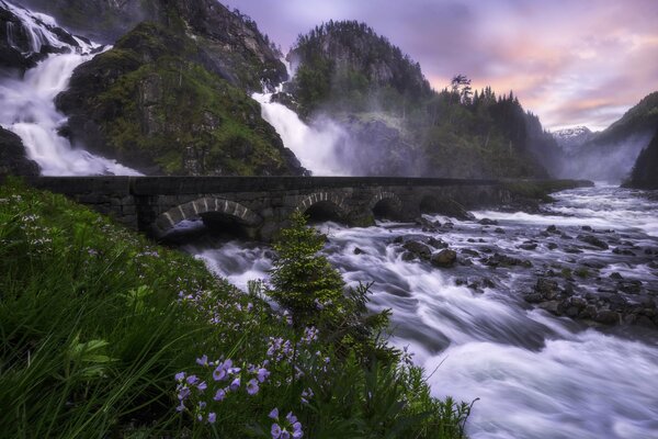 Norwegischer Wasserfall, der unter einer Brücke fließt