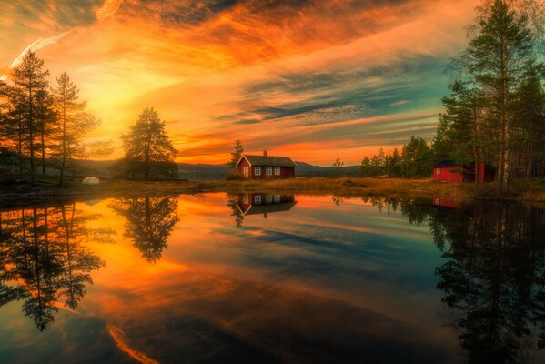 Una casa que se refleja en el lago en el fondo de una hermosa puesta de sol