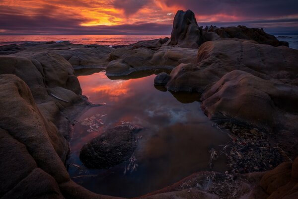 Puesta de sol en el fondo de las rocas y el océano