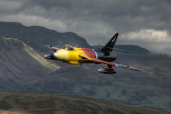 Ein Hawker hunter-Flugzeug fliegt in der Nähe der Berge