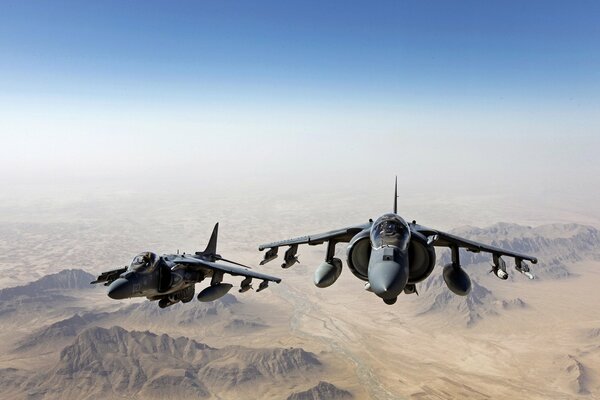 Un par de aviones de combate volando en el cielo sobre las montañas