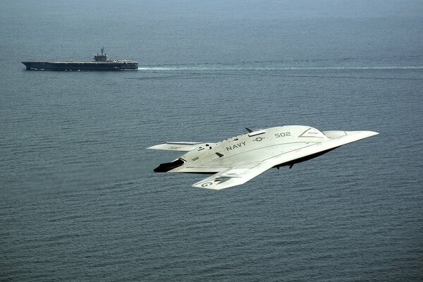 A combat drone against the background of the ocean and an aircraft carrier