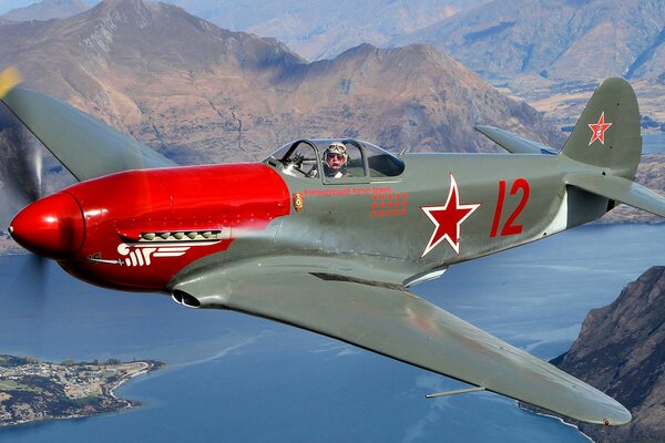 Yak-3A-combattente sovietico in volo su un paesaggio montuoso