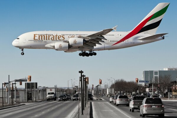 Emirates airline plane flies over the highway