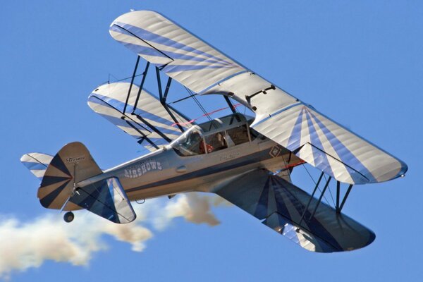 Biplane, paraglider in the sky, smoke from the nozzle